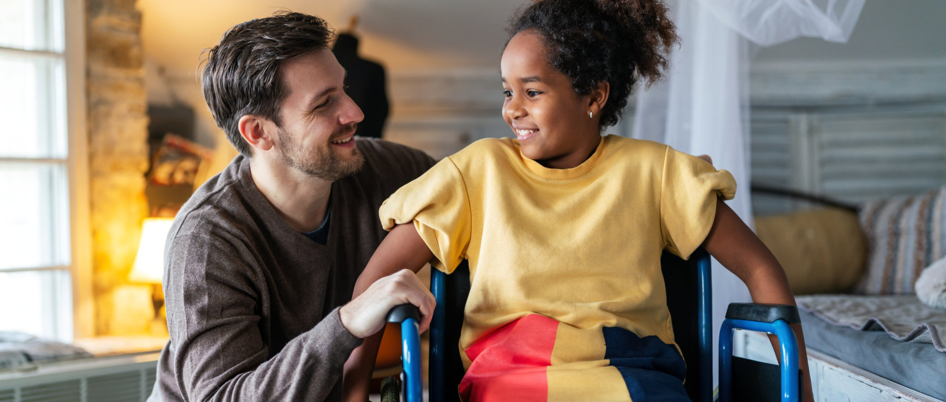 a man smiling at the little girl in a wheelchair