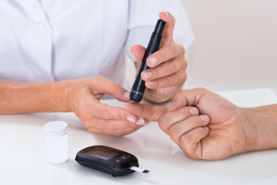 Close-up Of Doctor Measuring Sugar Reading Of Patient With Glucometer